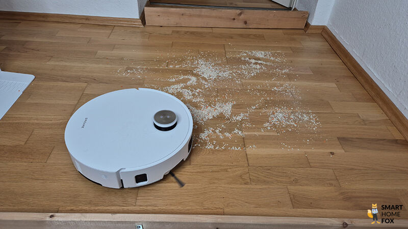 Der Dreame Matrix 10 Ultra saugt Linsen und Sand auf einem Hartboden.